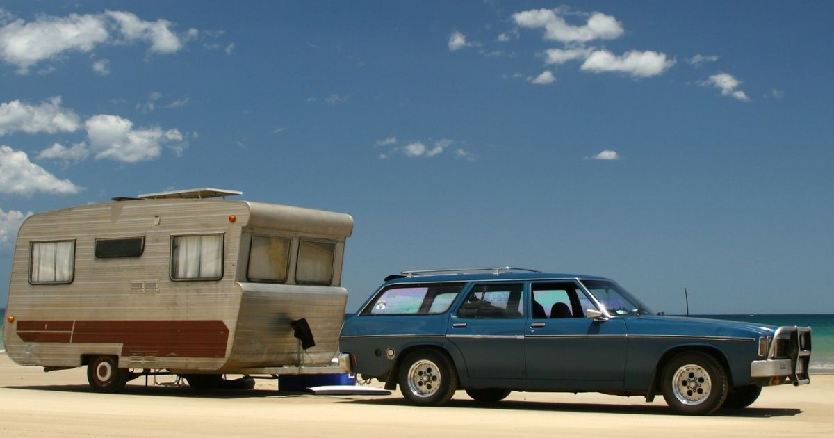 Caravane vintage tractée par voiture ancienne sur la plage